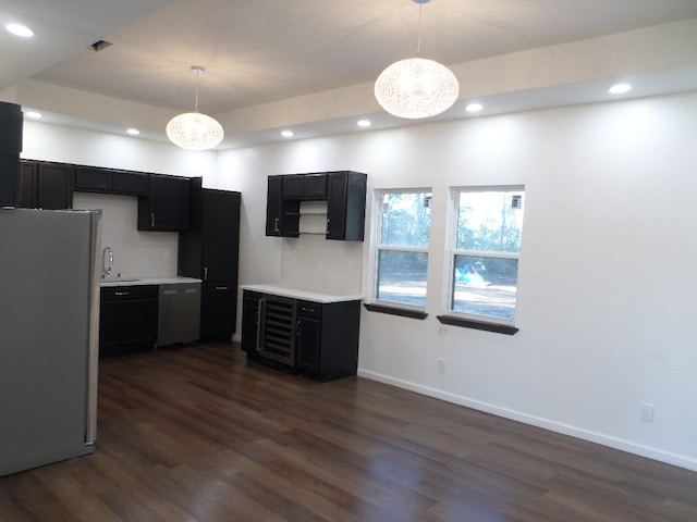 kitchen featuring sink, stainless steel fridge, dishwasher, dark hardwood / wood-style floors, and decorative light fixtures