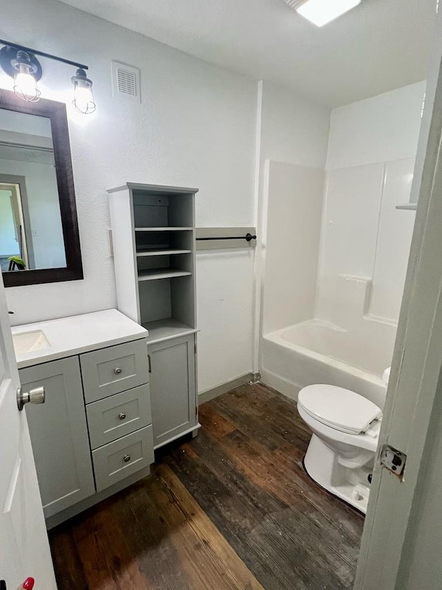 full bathroom with shower / tub combination, vanity, hardwood / wood-style flooring, and toilet