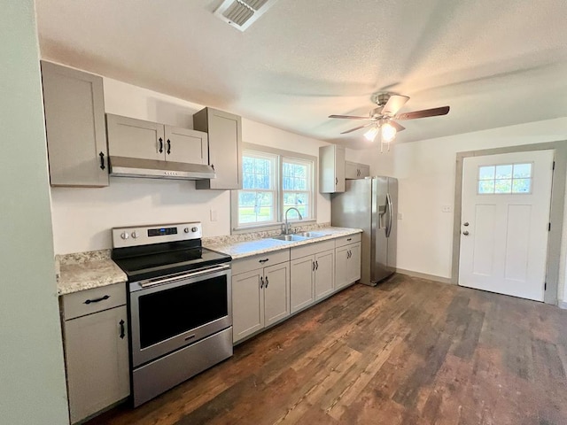 5233 Coffee Rd, Thomasville, GA 31792 - kitchen featuring appliances with stainless steel finishes, under cabinet range hood, light countertops, a sink, and dark wood-style flooring
