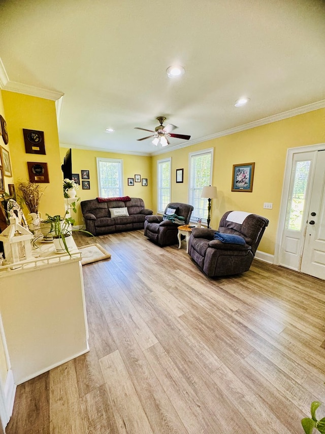 living room with crown molding, plenty of natural light, ceiling fan, and light wood-type flooring