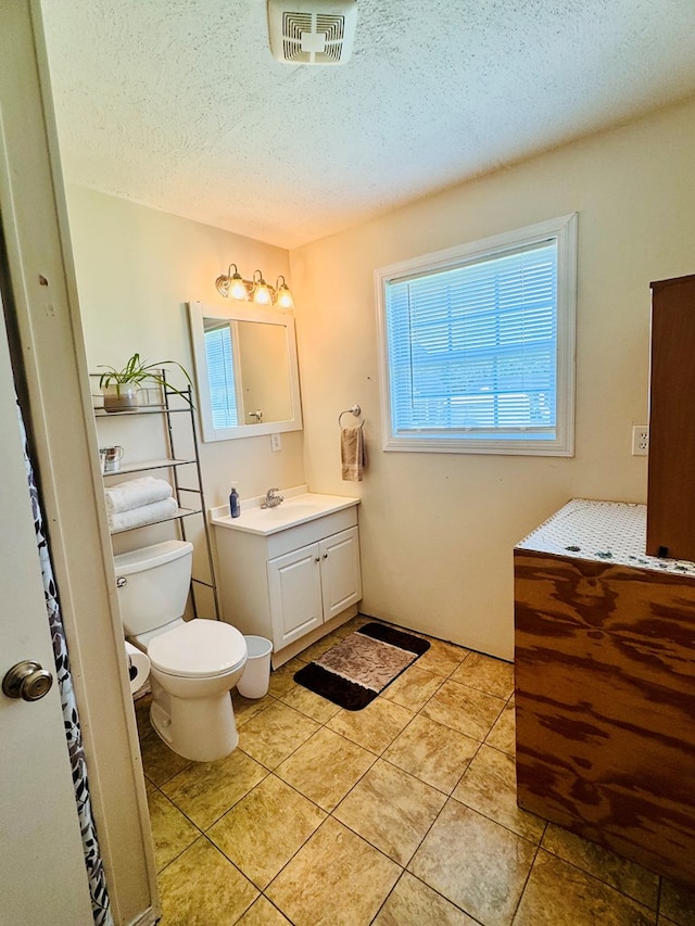 bathroom featuring tile patterned flooring, a textured ceiling, vanity, and toilet