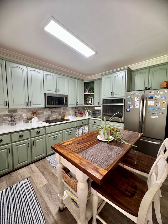 kitchen featuring ornamental molding, stainless steel appliances, green cabinetry, and light hardwood / wood-style floors