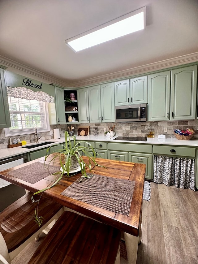 kitchen featuring sink, green cabinets, crown molding, decorative backsplash, and hardwood / wood-style flooring