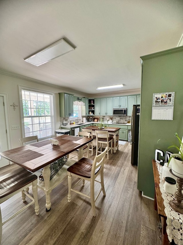 dining space with light hardwood / wood-style floors, crown molding, and sink