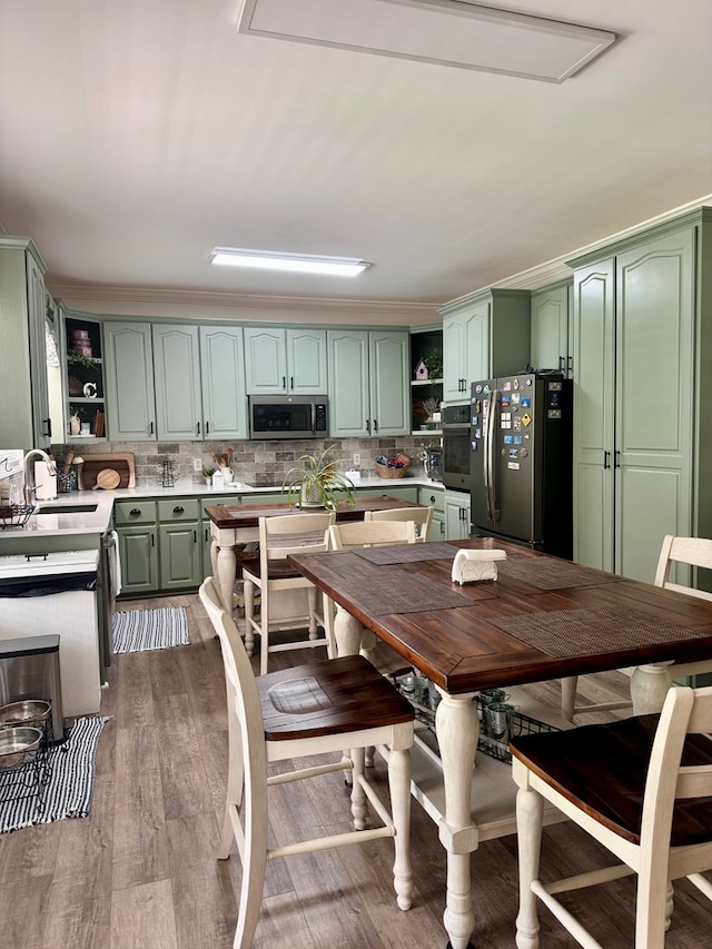 kitchen with sink, green cabinetry, tasteful backsplash, dark hardwood / wood-style flooring, and stainless steel appliances