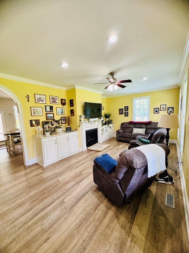 living room with ceiling fan, ornamental molding, and light hardwood / wood-style flooring