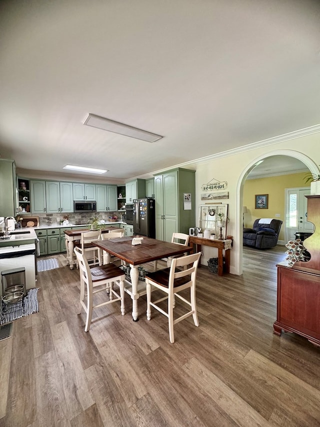 dining space with crown molding, sink, and dark wood-type flooring