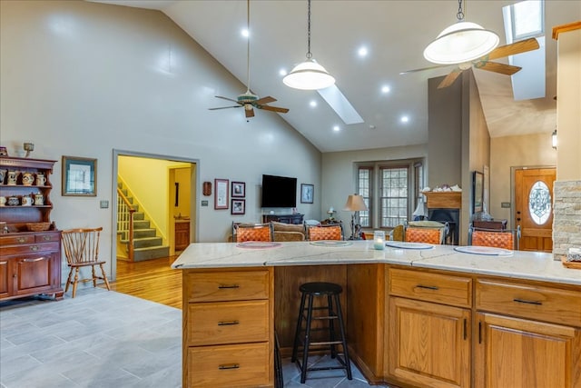 kitchen with ceiling fan, open floor plan, a skylight, and decorative light fixtures