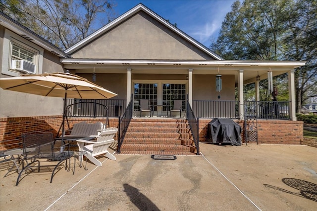 view of front of house with cooling unit, a porch, a patio, and stucco siding