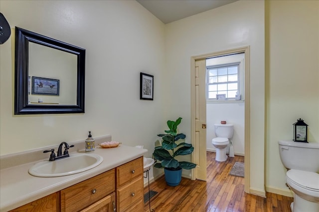 bathroom with baseboards, vanity, toilet, and hardwood / wood-style flooring