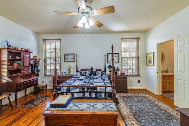 bedroom featuring multiple windows, baseboards, and wood finished floors