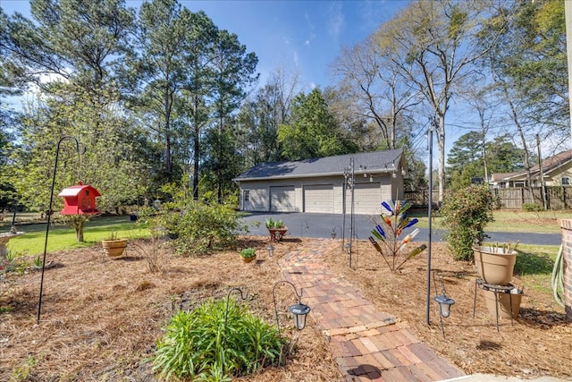 view of yard featuring a garage, fence, and an outbuilding