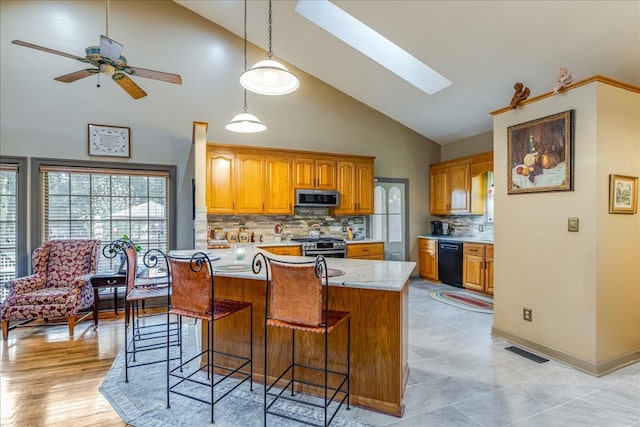 kitchen with stainless steel appliances, brown cabinetry, a breakfast bar area, and visible vents