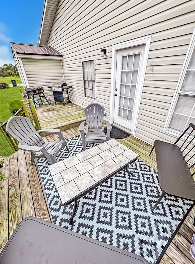 wooden terrace with a grill and outdoor dining space