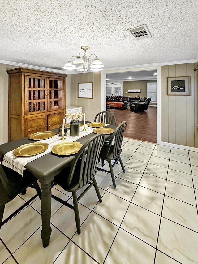 dining space featuring light tile patterned floors, visible vents, an inviting chandelier, ornamental molding, and a textured ceiling