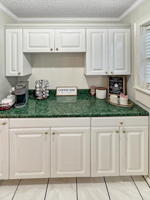 kitchen featuring dark countertops, white cabinetry, ornamental molding, decorative backsplash, and a textured ceiling