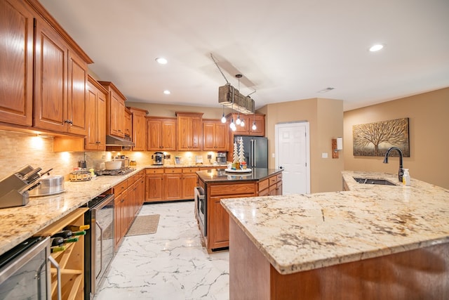 kitchen with appliances with stainless steel finishes, sink, pendant lighting, and an island with sink