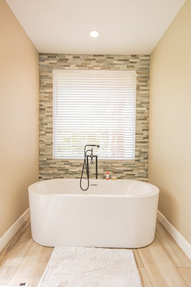 bathroom featuring hardwood / wood-style floors and a tub to relax in