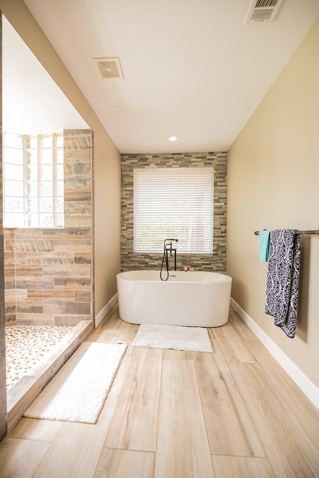 bathroom with wood-type flooring and a bath