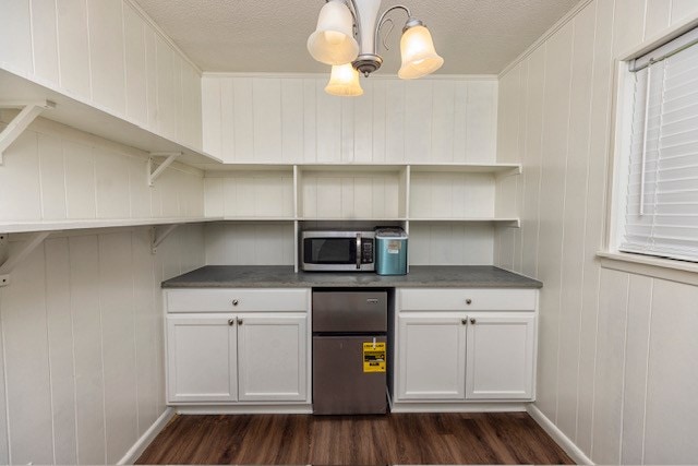 kitchen with white cabinets, decorative light fixtures, dark hardwood / wood-style flooring, and stainless steel appliances