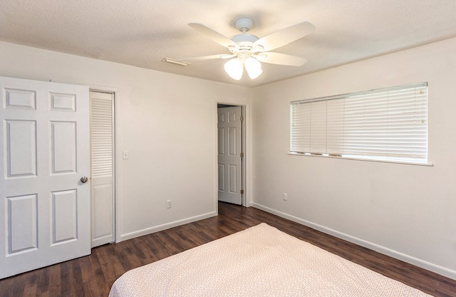 bedroom with a closet, ceiling fan, and dark wood-type flooring