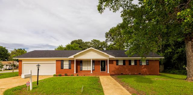 ranch-style house with covered porch, a garage, and a front yard