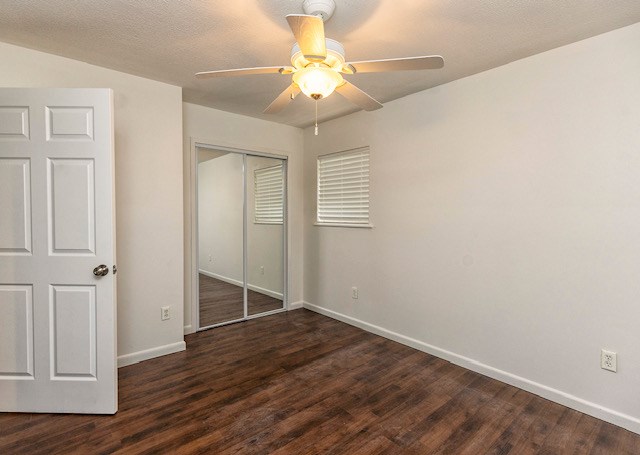 unfurnished bedroom featuring a closet, ceiling fan, dark hardwood / wood-style flooring, and a textured ceiling