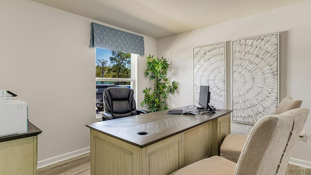 office featuring light wood-type flooring and a textured ceiling