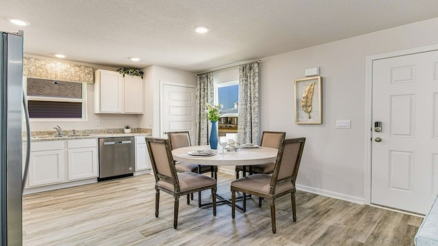 dining room featuring a textured ceiling, light hardwood / wood-style flooring, and sink