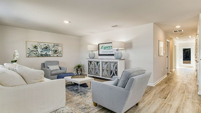 living room with a textured ceiling and light hardwood / wood-style flooring