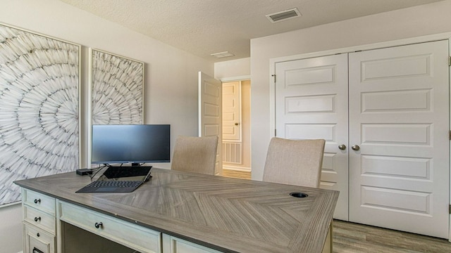 office area with a textured ceiling and light hardwood / wood-style floors