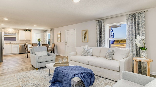 living room featuring a textured ceiling, light wood-type flooring, and sink