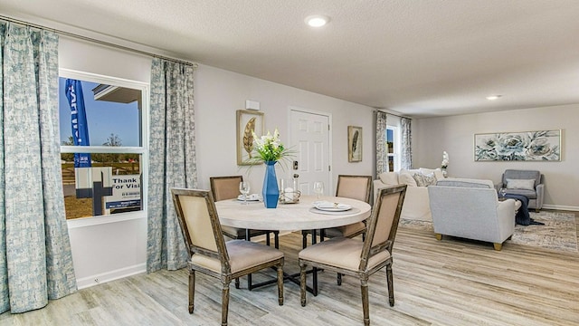 dining space featuring light hardwood / wood-style floors and a textured ceiling