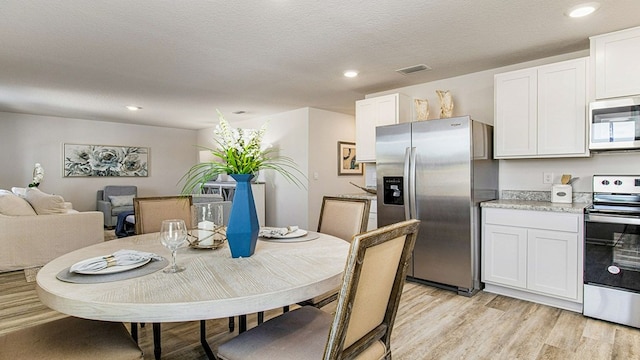 dining space featuring a textured ceiling and light hardwood / wood-style flooring