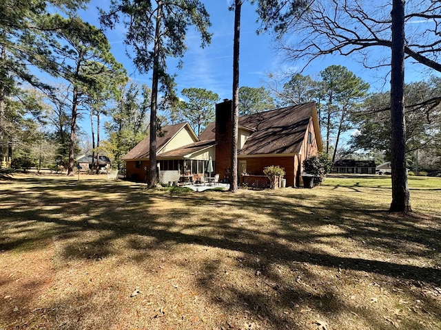 view of side of property featuring a yard, a chimney, and a patio area