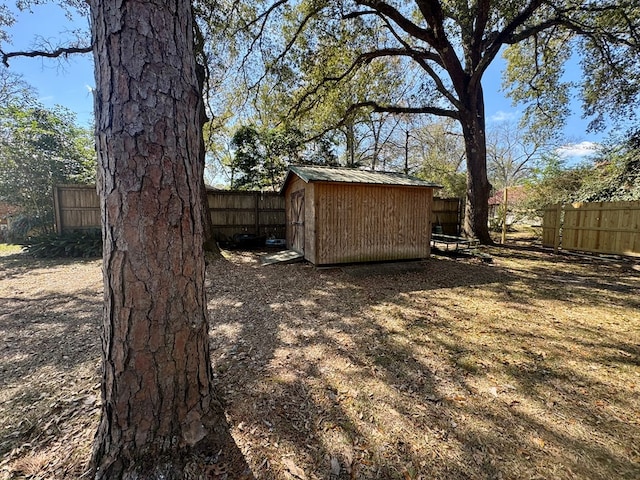 view of yard featuring an outbuilding, a fenced backyard, and a storage shed