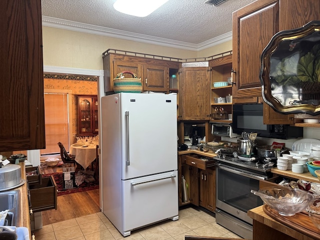 kitchen with wallpapered walls, stainless steel electric range oven, freestanding refrigerator, a textured ceiling, and black microwave