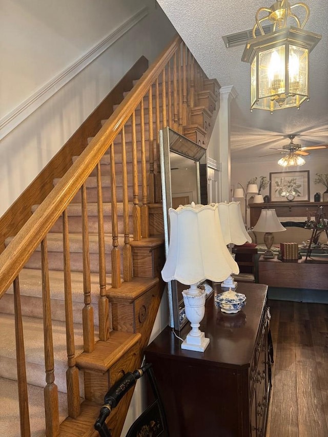 stairs featuring ceiling fan, a textured ceiling, and wood finished floors