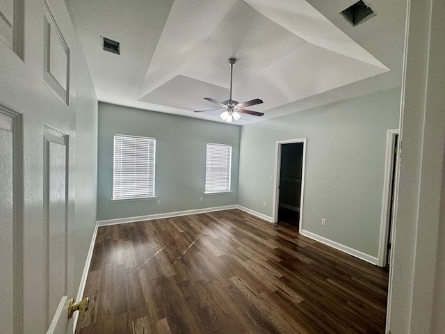 interior space featuring a raised ceiling, dark hardwood / wood-style floors, and ceiling fan