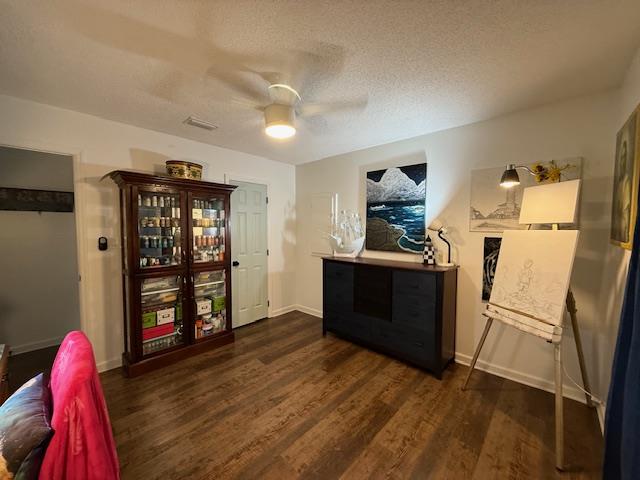 interior space with a textured ceiling, dark hardwood / wood-style flooring, and ceiling fan