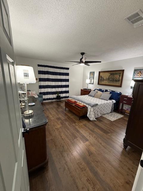 bedroom featuring ceiling fan, dark hardwood / wood-style flooring, and a textured ceiling