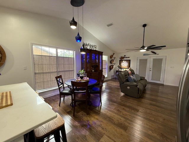 dining room with ceiling fan, dark wood-type flooring, and vaulted ceiling