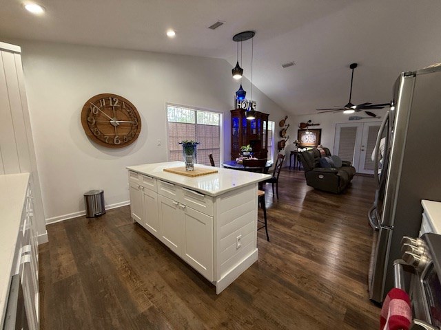 kitchen featuring pendant lighting, white cabinets, ceiling fan, stainless steel fridge, and a kitchen island