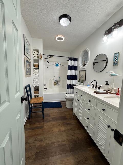 full bathroom with shower / bath combination with curtain, vanity, a textured ceiling, hardwood / wood-style floors, and toilet