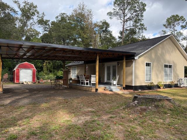 view of front facade featuring a front lawn, a storage unit, and french doors