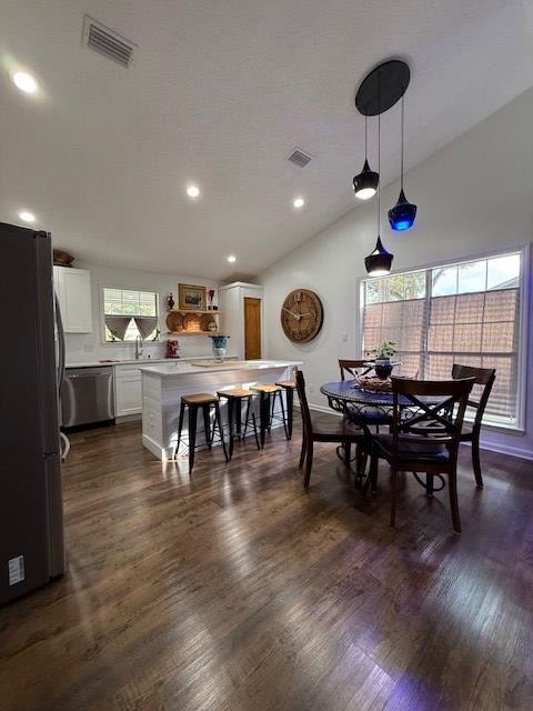 dining area featuring dark hardwood / wood-style flooring and vaulted ceiling