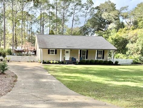 ranch-style home featuring covered porch and a front yard