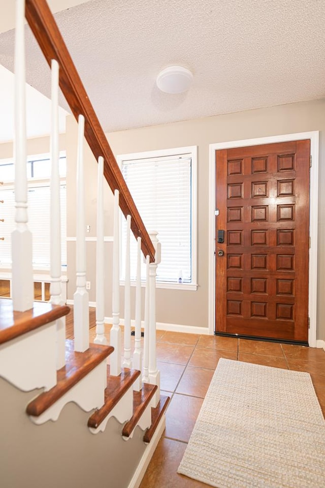 entryway featuring light tile patterned floors and a textured ceiling