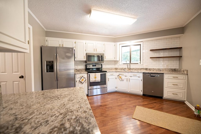 kitchen with white cabinetry, sink, crown molding, hardwood / wood-style floors, and appliances with stainless steel finishes