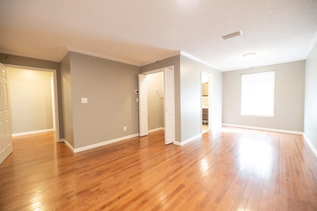 empty room with crown molding, light hardwood / wood-style flooring, and a textured ceiling